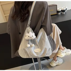 Détail du sac cabas plissé argenté avec logo métallique et breloque peluche