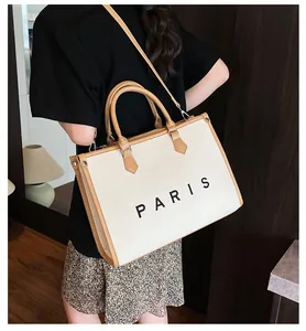 Detail of large canvas tote bag with PARIS print and brown leather trim accents