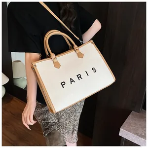 Detailed shot of canvas tote bag with brown leather handles and Paris print lettering