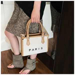 Detail of canvas tote bag with brown leather trim and Paris text worn by a model