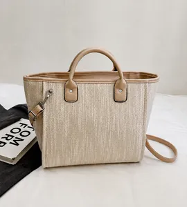 Detailed top view of a woven tote bag with brown leather handles and silver hardware