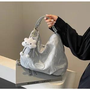 Gros plan du sac hobo plissé argenté avec breloque nuage et étiquette de marque