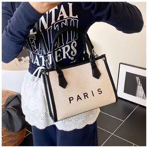 Detail of canvas tote bag with PARIS lettering and black leather trim for shoulder wear