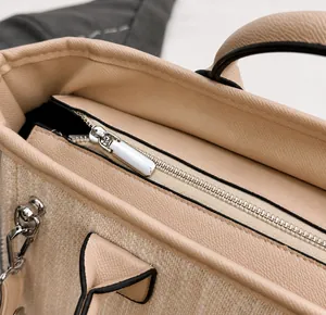 Detail of silver smooth metal zipper on beige leather and woven canvas bucket bag