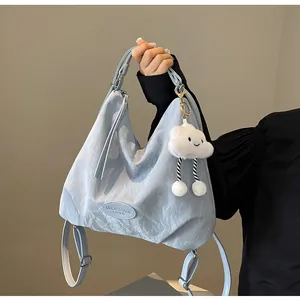 Détail du sac bleu clair avec étiquette en cuir et pendentif peluche nuage blanc décoratif