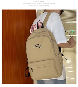 Detail of a khaki minimalist backpack featuring a front zipper pocket and durable nylon texture