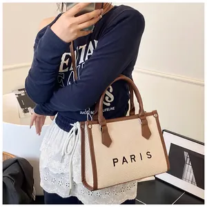 Detail of canvas tote with PARIS logo and brown leather handles on a female model