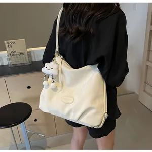 Détail du cabas plissé crème brillant avec breloque nuage en peluche et logo en métal