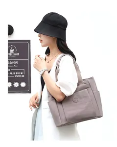 Side view of large mauve nylon tote bag with wide shoulder straps worn by a model