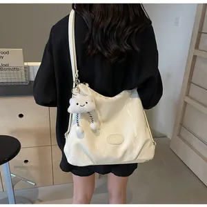 Détail du sac cabas en cuir PU crème avec breloque nuage en peluche et plaque de marque