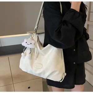 Gros plan du sac cabas en cuir froissé crème avec pendentif nuage et logo gravé