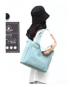 Detail of mint green nylon tote bag showing wide shoulder strap and side pocket design