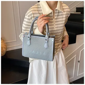 Detailed close-up of a blue woven tote bag with white Paris embroidery and leather trim