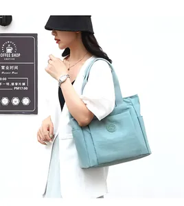 Light blue nylon tote bag with multiple pockets shown on model in a street style shot