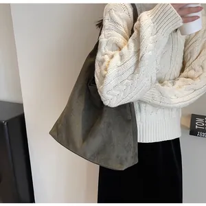 Green suede tote bag worn by a model in a cozy white sweater for autumn and winter style