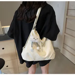 Détail du sac à bandoulière en cuir verni blanc crème avec un charme nuage pelucheux