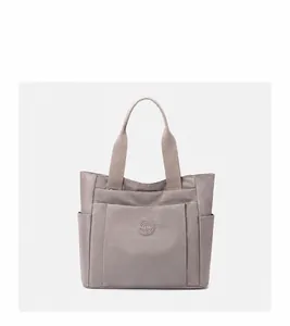 Macro detail of high-quality nylon fabric texture and reinforced stitching on a grey tote bag
