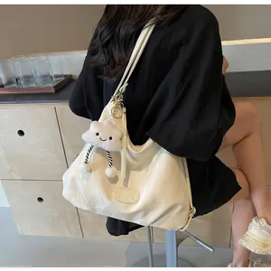 Vue détaillée du grand sac crème en cuir verni avec une breloque nuage en peluche douce