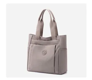 Detail of taupe nylon handbag featuring front zipper pocket and round 'B' logo plaque