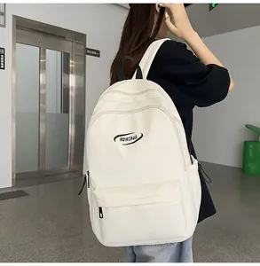Modern minimalist cream backpack shown from back view on model in urban building setting