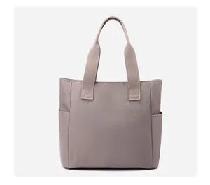 Detail view of large nylon tote bag featuring side pockets and durable woven handles