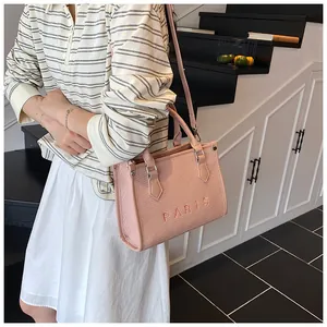 Pink tote bag detail featuring PARIS embroidery and adjustable crossbody strap on model