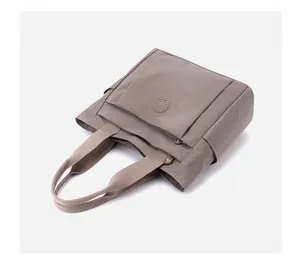 Detail view of khaki nylon tote bag featuring multiple pockets and durable fabric texture