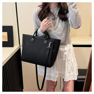 Detalle del bolso tote negro trenzado con asas dobles y herrajes plateados finos