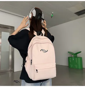 Close-up of the light pink nylon backpack featuring multi-layer zipper pockets and ample storage