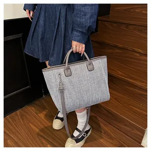 Detalle de la textura tejida gris y el asa de cuero de este bolso tote tipo cubo