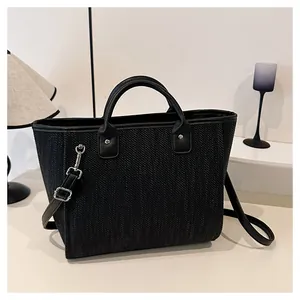 Detalle del bolso de cubo trenzado negro con patrón de textura y correa ajustable