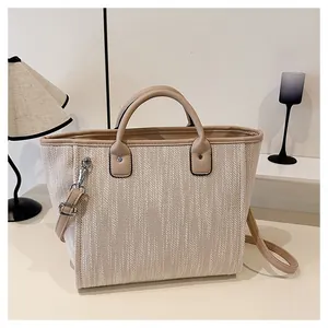 Detalle de la textura tejida y los bordes de cuero sintético de un bolso tote beige