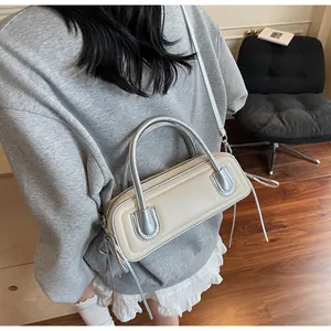 Dettaglio borsa a tracolla beige con manico in metallo argento e cinturino laterale
