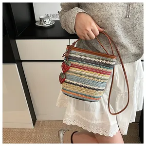 Détail d'un sac seau tissé coloré avec breloques fraises et poignées en cuir marron