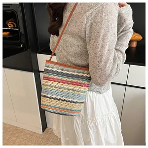 Détail d'un sac seau tissé coloré avec bandoulière en cuir porté par une femme en décor