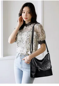 Detail of black pebbled leather hobo bag with multiple pockets and silver metal hardware