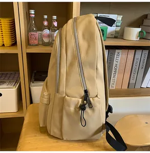 Detail view of khaki school backpack with multi-zipper compartments on a wooden bench
