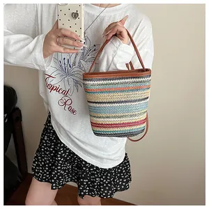 Détail du sac seau en paille tissée colorée avec poignée en cuir marron et rayures