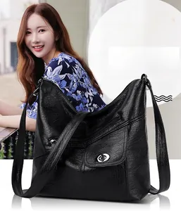 Detail of black faux leather shoulder bag featuring multi-pocket zippers and metal twist lock