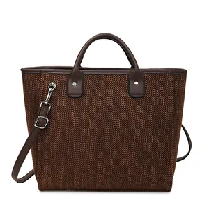 Detalle de textura tejida y asas de cuero marrón oscuro en un bolso estilo bucket