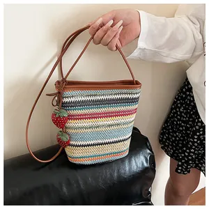 Détail du sac seau tissé coloré avec breloques fraises et bandoulière en cuir souple