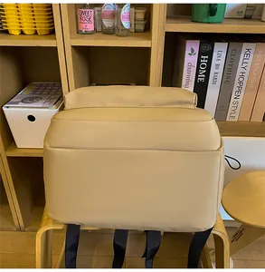 Detailed back and bottom view of a large beige nylon backpack on a wooden chair