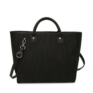 Detalle del bolso de cubo tejido negro con herrajes plateados y correa ajustable