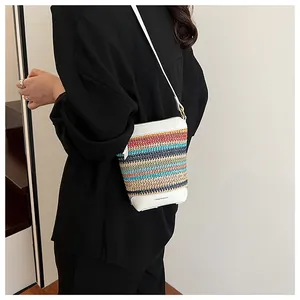 Detail of multi-color striped woven crossbody bag with white leather base and logo