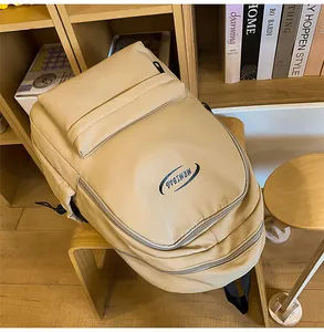 Detailed view of beige MRMIBAG backpack with logo and zippers on a wooden chair