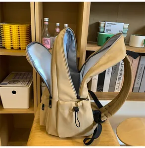 Interior view of khaki backpack showing spacious compartments and grey lining on a wooden chair