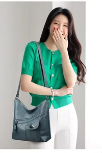 Detail of teal leather shoulder bag with multiple pockets and metal swivel lock on model