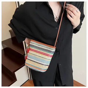 Détail du sac seau tissé coloré avec breloque fraise et bandoulière marron en cuir
