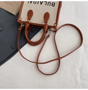 Detailansicht der bestickten Canvas-Tasche mit braunen Ledergriffen und Schultergurt