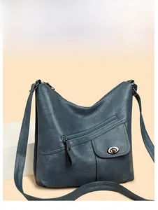 Detail view of dark blue leather shoulder bag with asymmetrical pockets and metal buckle
